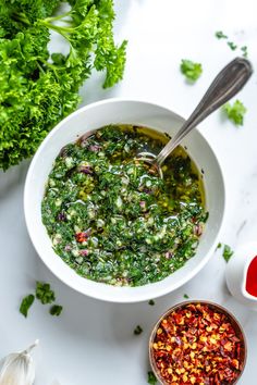 a white bowl filled with green food next to two bowls full of red and yellow vegetables