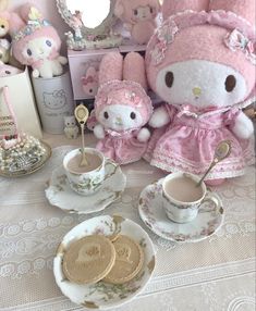 a table topped with tea cups and saucers covered in pink teddy bears sitting next to each other