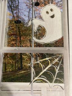 a window decorated with spider webs and a ghost on it's back side