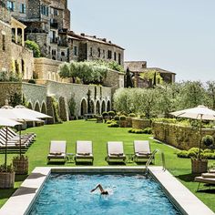 an outdoor swimming pool surrounded by lawn chairs and umbrellas