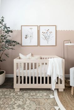 a baby's room with two framed pictures on the wall and a crib