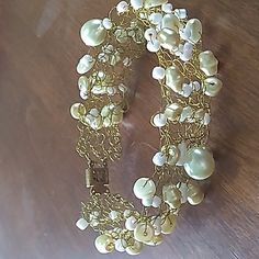 a close up of a bracelet on a wooden table with beads and chains attached to it