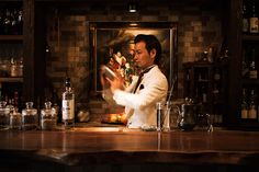 a man standing at a bar preparing drinks