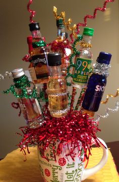 a cup filled with lots of bottles and tinsel on top of a wooden table