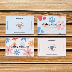 three different business cards on top of a wooden table with flowers and dog paw prints