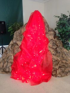 a red dress sitting on top of a table next to a potted green plant