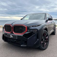 the front end of a grey suv parked on top of a parking lot next to the ocean