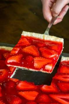 someone cutting into a strawberry pie with a knife