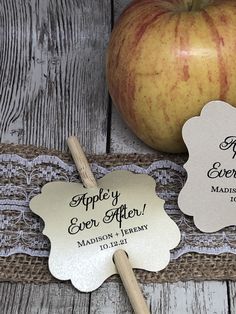 an apple sitting on top of a wooden table next to two tags with the words happily ever after