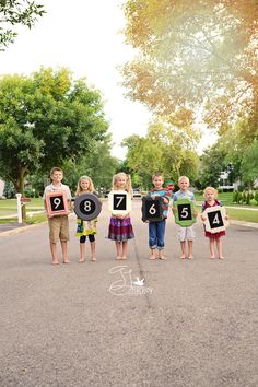 a group of children standing in the middle of a road holding up signs with numbers on them