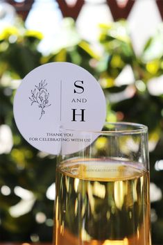 a glass filled with liquid sitting on top of a table next to a sign that says su and h