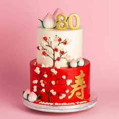 a three tiered cake decorated with flowers and gold numbers on the top, sitting on a plate against a pink background