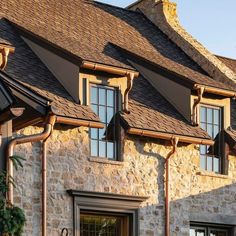 a stone house with brown shingles and windows