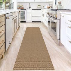 a kitchen with white cabinets and an area rug on the floor in front of the stove