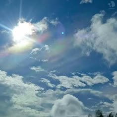 the sun shines brightly through the clouds in this blue sky with palm trees on either side