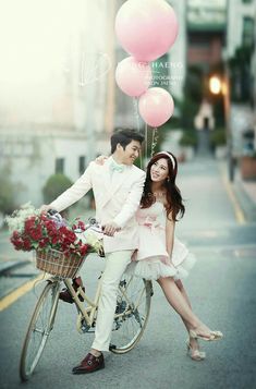 a man and woman on a bicycle with balloons