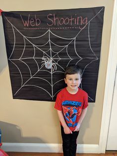 a young boy standing in front of a web shooting sign