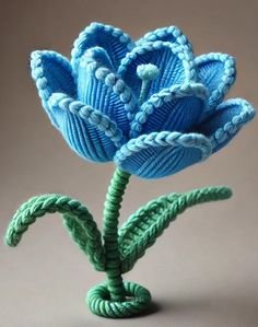 a blue flower made out of yarn sitting on top of a table