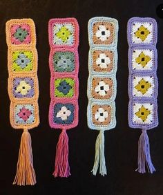 four crocheted bookmarks with flowers and tassels on them, all lined up against a black background