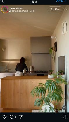 a woman standing at the kitchen counter in front of a potted plant and an oven