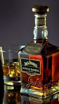 a bottle of jack daniels single barrel whiskey next to two glasses on a reflective surface