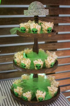 three tiered trays with rice and green decorations on them, each topped with frog eyes