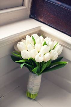 a bouquet of white tulips in a vase on the window sill,