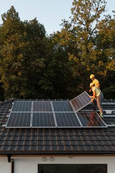 two men are working on the roof of a house that has solar panels on it