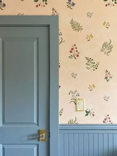 an open door in a room with floral wallpaper on the walls and blue doors