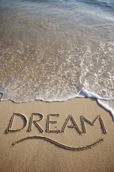 the word dream written in the sand at the beach