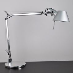 a desk lamp sitting on top of a table next to a white wall and floor