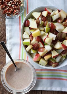 apples, grapes and nuts are in a bowl next to a glass of smoothie