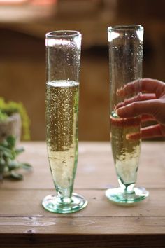 two champagne flutes are being filled with liquid