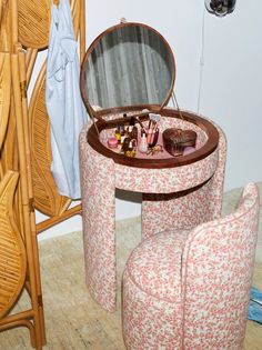 a vanity table and stool with an open mirror on the top, next to a wicker chair