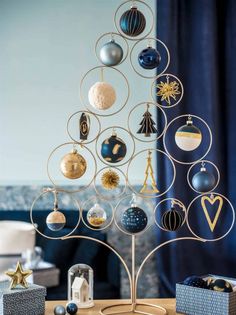 a christmas tree with ornaments hanging from it's sides on a table in front of a window