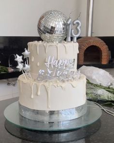 a birthday cake with white frosting and decorations on top is sitting on a table in front of a fireplace