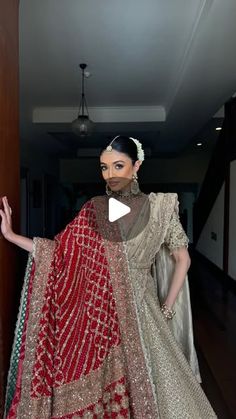 a woman in a red and gold bridal gown standing next to a door with her hands out