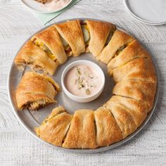 there is a large pastry on the plate with a small bowl of dip in it