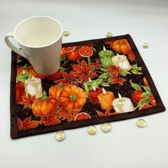 a coffee cup sitting on top of a place mat with pumpkins and poinsettis