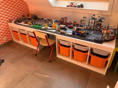 a toy table with legos on it and orange chairs in front of the table