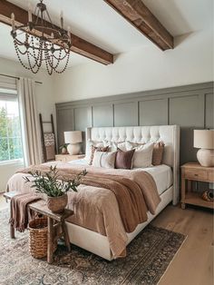 a large bed sitting in a bedroom under a chandelier next to a window