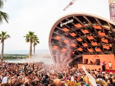 a large group of people are gathered at an outdoor concert with the stage set up