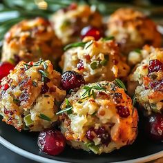 a black plate topped with crab cakes covered in cranberry sauce and garnished with herbs