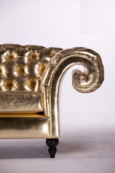 a gold colored couch sitting on top of a white floor