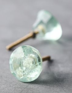 two green glass knobs sitting on top of a gray table next to each other