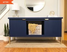 a blue sideboard with gold accents and a round mirror on the wall above it