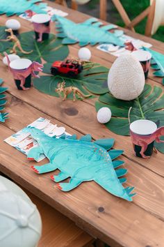 a wooden table topped with lots of paper cut outs and dinosaurs sitting on top of it