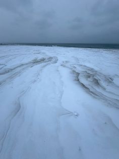 an expanse of snow covered ground next to the ocean