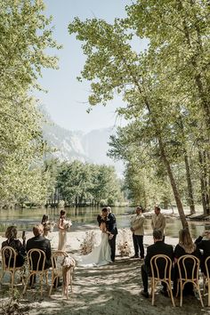 a couple getting married in front of an outdoor ceremony area with chairs and trees around them