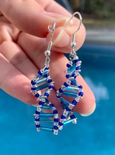 a pair of blue and clear glass beaded earrings on a person's hand